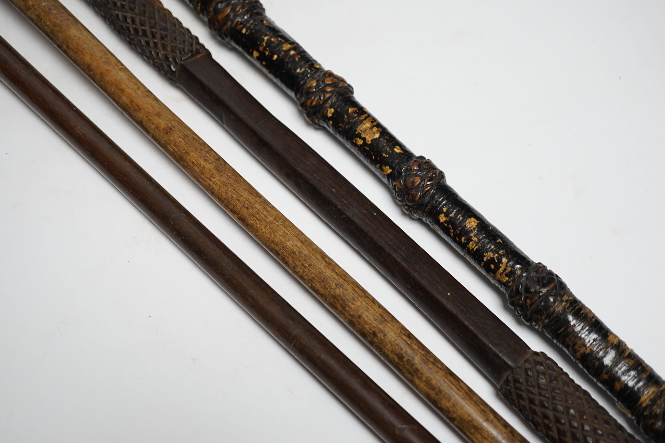 A ceremonial sword stick with removable brush end, a 19th century continental carved head with glass eyes on associated cane stick and two others, longest 93cm